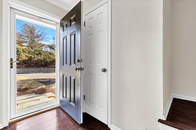 doorway to outside featuring dark wood finished floors, crown molding, and baseboards