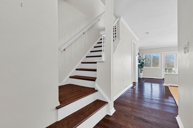 staircase with wood finished floors, crown molding, and baseboards