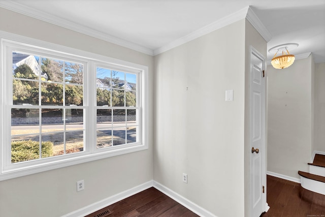 empty room featuring dark wood finished floors, crown molding, and baseboards