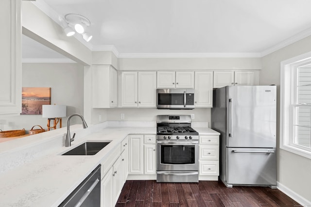 kitchen with dark wood finished floors, ornamental molding, appliances with stainless steel finishes, white cabinetry, and a sink