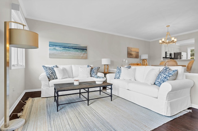 living room with baseboards, a notable chandelier, wood finished floors, and crown molding