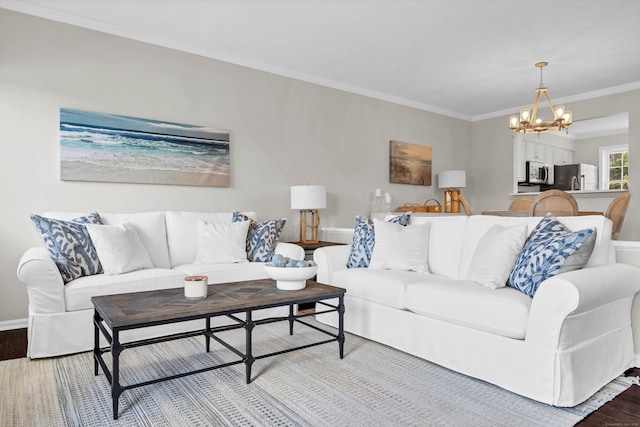 living area with wood finished floors, baseboards, ornamental molding, and an inviting chandelier
