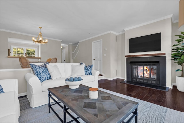 living room featuring wood finished floors, an inviting chandelier, a lit fireplace, baseboards, and ornamental molding