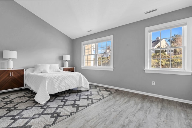 bedroom with visible vents, multiple windows, baseboards, and wood finished floors