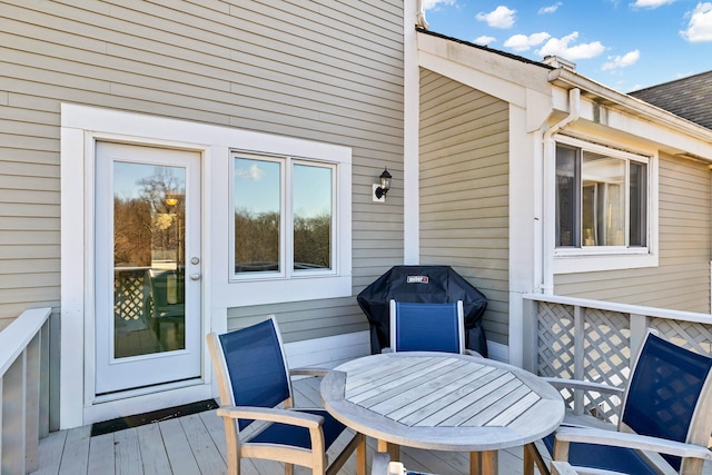 wooden deck with outdoor dining space and area for grilling