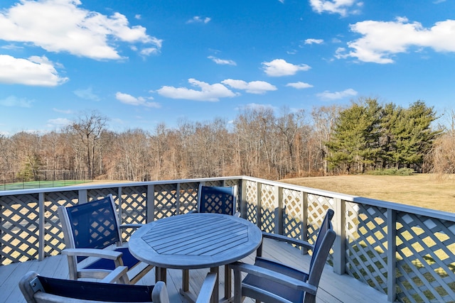 wooden deck with outdoor dining area and a view of trees
