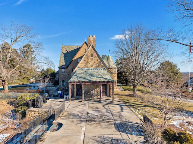 exterior space featuring stucco siding, a high end roof, and a chimney