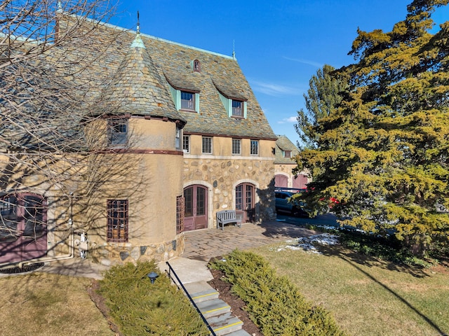 view of front of house with a high end roof, stucco siding, french doors, and stone siding