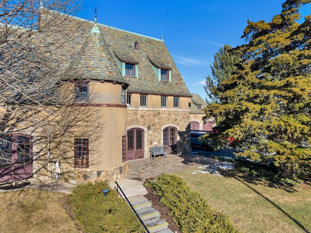 view of front of house featuring stone siding, a high end roof, and stucco siding