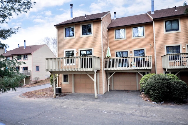 rear view of house featuring central air condition unit, driveway, and an attached garage