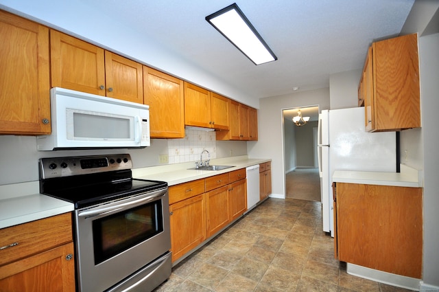 kitchen with a sink, white appliances, tasteful backsplash, and light countertops