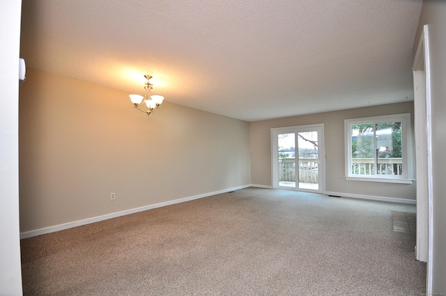 empty room featuring baseboards, carpet, an inviting chandelier, and a textured ceiling