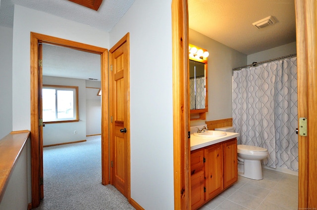 full bath featuring vanity, toilet, visible vents, and a textured ceiling