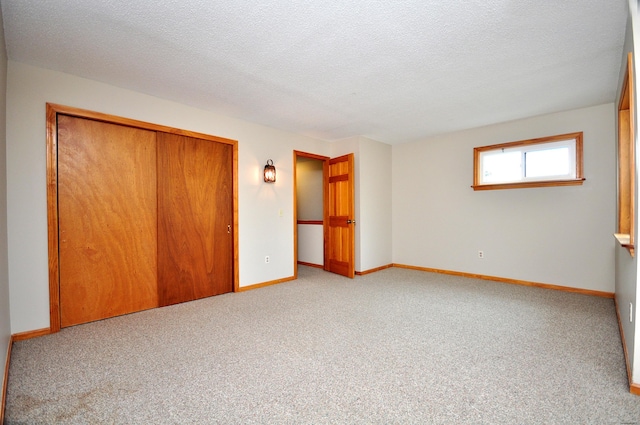 unfurnished bedroom with a closet, baseboards, a textured ceiling, and carpet floors