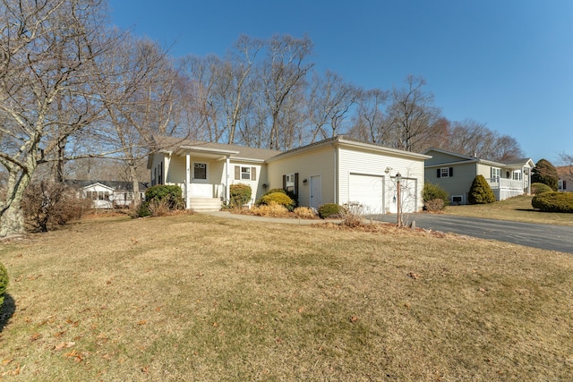 ranch-style home with aphalt driveway, covered porch, an attached garage, and a front yard