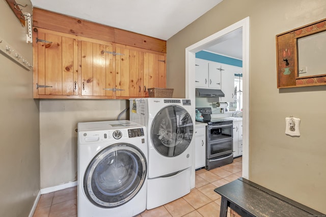 washroom with light tile patterned floors, washing machine and dryer, and baseboards