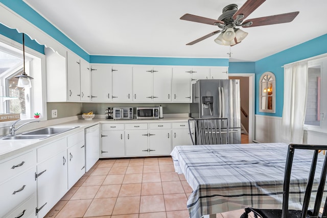 kitchen with light tile patterned floors, a sink, stainless steel appliances, light countertops, and white cabinets