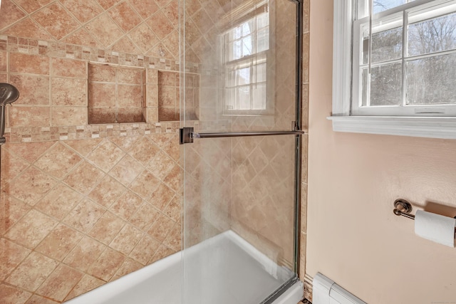 bathroom featuring a shower with door, a baseboard heating unit, and a wealth of natural light