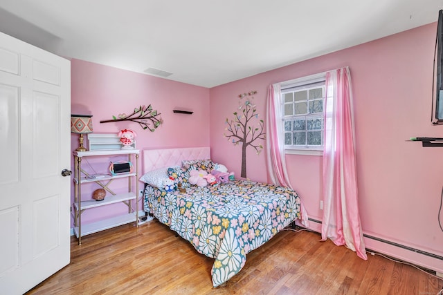 bedroom with visible vents, wood finished floors, and a baseboard radiator