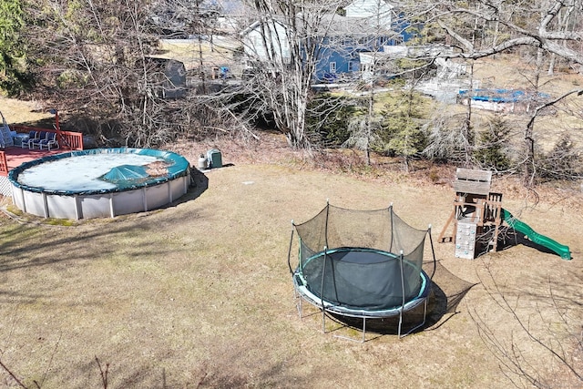 view of yard with a covered pool, a trampoline, and a playground