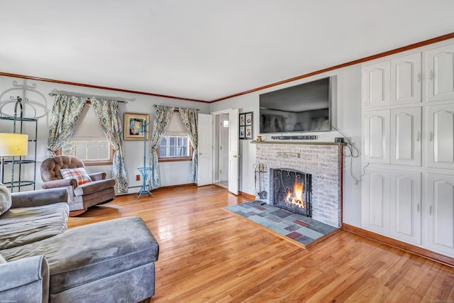 living room with baseboards, light wood-style flooring, a fireplace, and crown molding