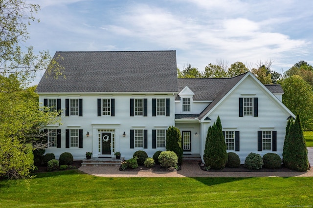 colonial inspired home featuring a front yard and a shingled roof