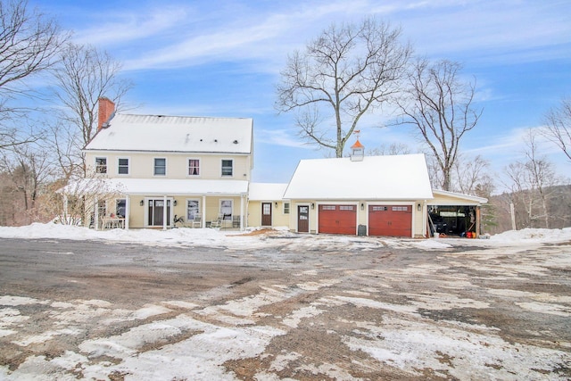 view of front of house with a garage, driveway, a carport, and a chimney