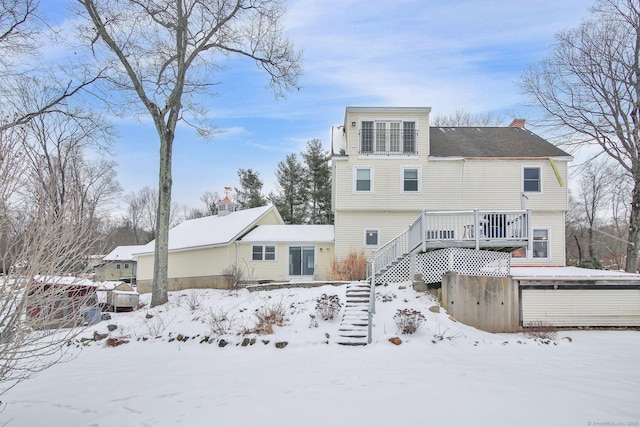 snow covered rear of property with stairway, a deck, and a chimney