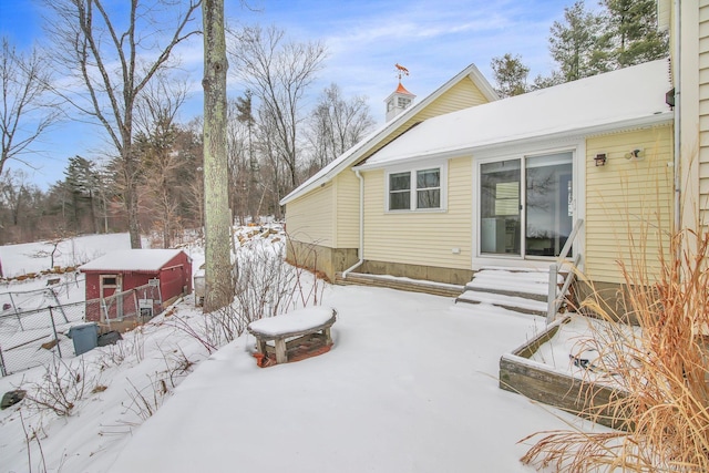 snow covered back of property with entry steps and fence