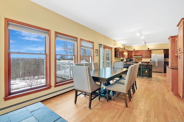 dining room with a baseboard heating unit, light wood-style flooring, and track lighting