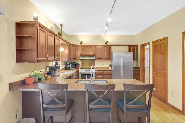 kitchen with a peninsula, open shelves, appliances with stainless steel finishes, and a sink