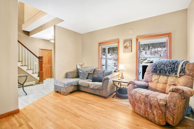 living area with a baseboard radiator, stairs, baseboards, and wood finished floors