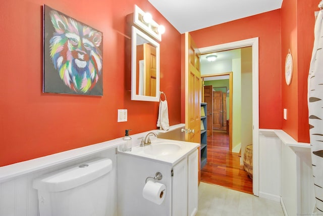 bathroom with toilet, wood finished floors, and vanity