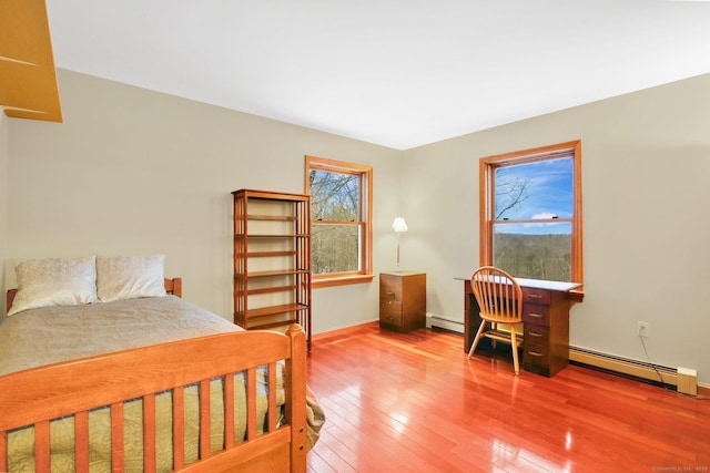 bedroom with baseboard heating, baseboards, and wood-type flooring