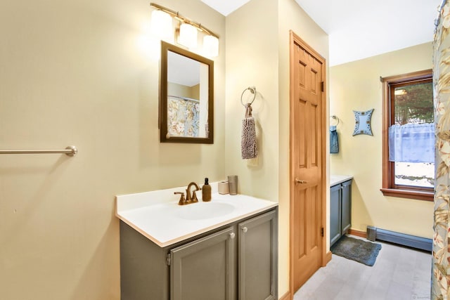 full bath featuring a baseboard heating unit, baseboards, wood finished floors, and vanity