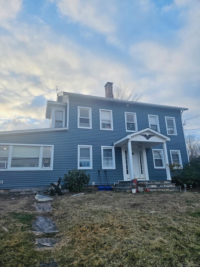 view of front facade featuring a chimney and a front lawn