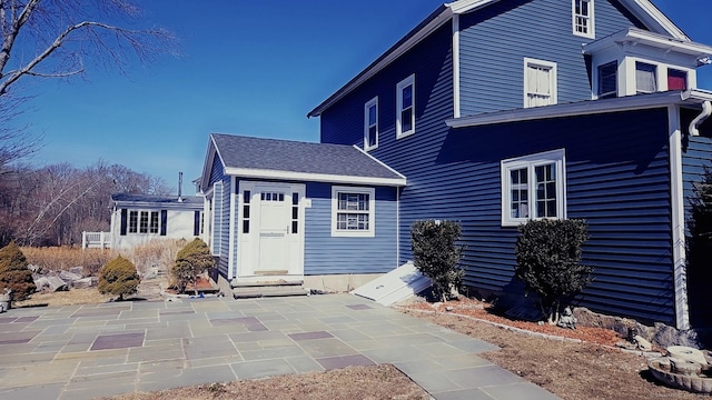 view of front of home with entry steps, a shingled roof, and a patio