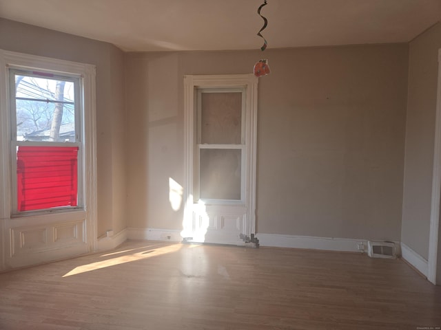 unfurnished room with visible vents, baseboards, and wood finished floors