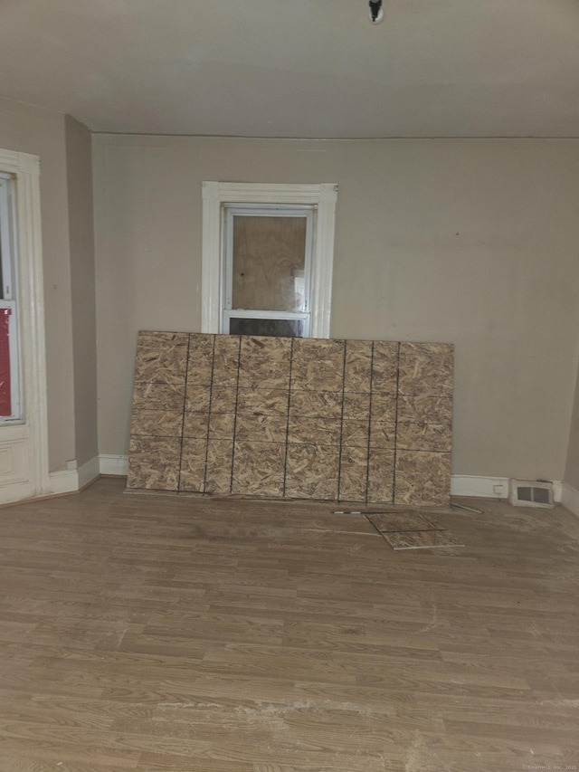 unfurnished room featuring visible vents, baseboards, and wood finished floors