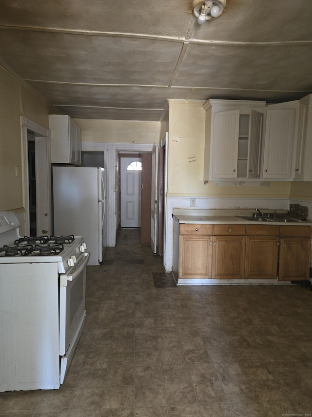 kitchen with a sink, white appliances, white cabinets, brown cabinetry, and light countertops