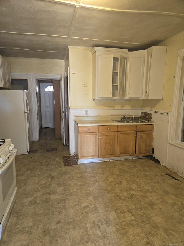 kitchen with brown cabinetry, white appliances, light countertops, and a sink