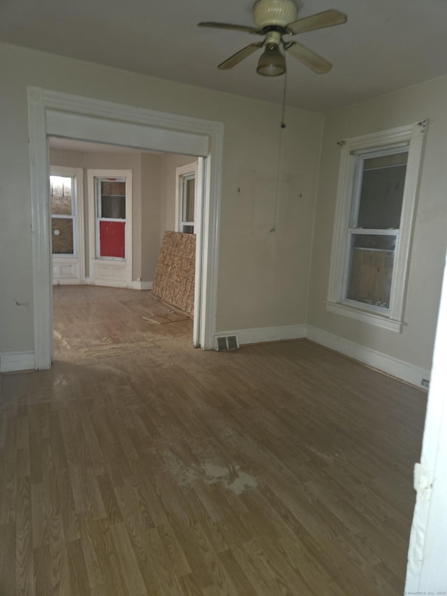 unfurnished room featuring visible vents, a ceiling fan, baseboards, and wood finished floors