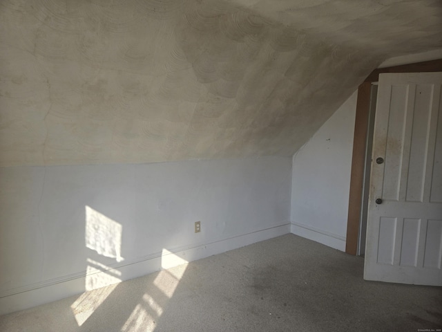 additional living space featuring carpet and vaulted ceiling