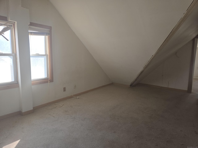 bonus room with light colored carpet, baseboards, and lofted ceiling