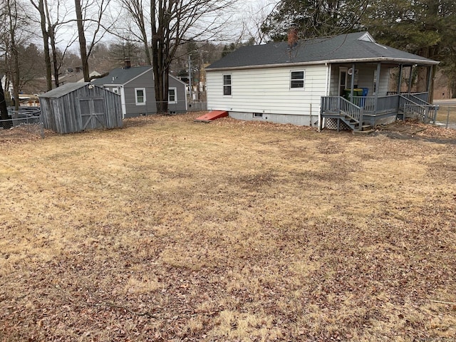 back of house with an outbuilding, fence, a porch, a chimney, and a storage shed