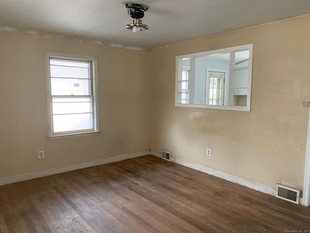 empty room featuring visible vents, baseboards, and wood finished floors