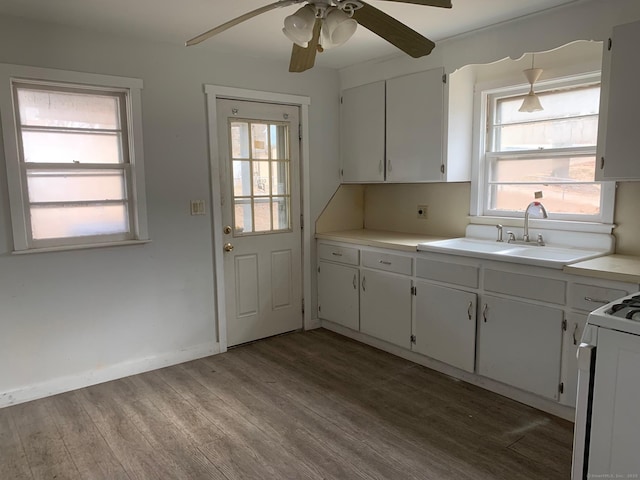 kitchen featuring wood finished floors, white cabinetry, a sink, light countertops, and range with gas cooktop