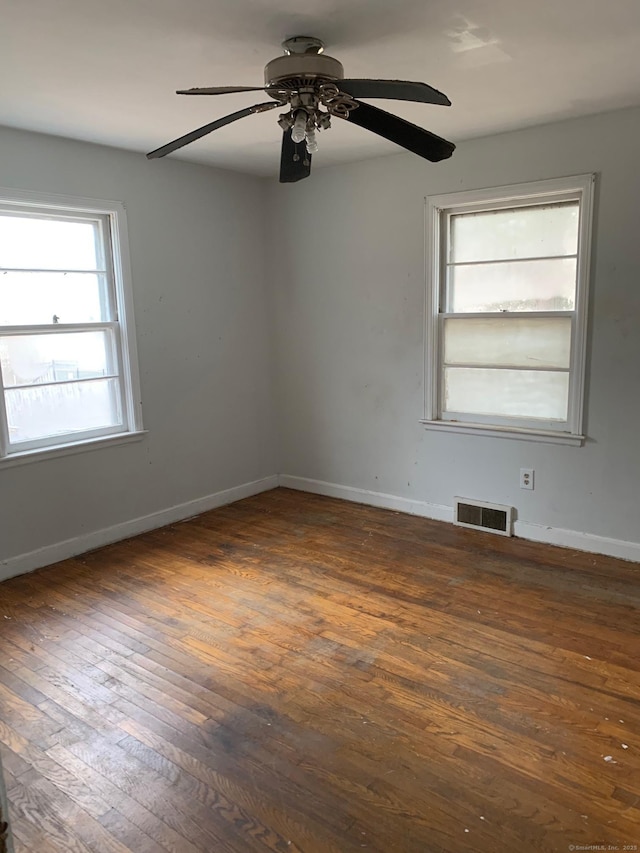 empty room featuring visible vents, baseboards, and wood-type flooring