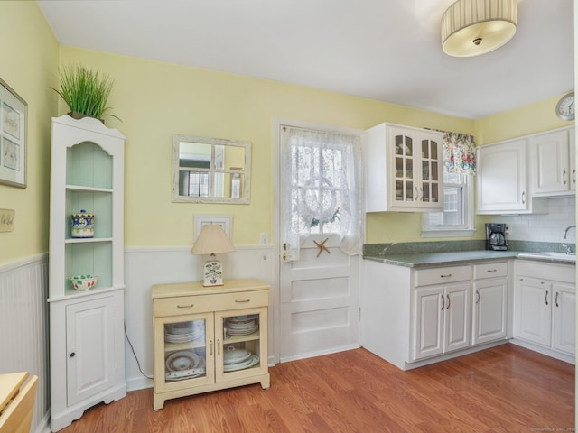 kitchen featuring a wainscoted wall, light wood-style floors, and white cabinets