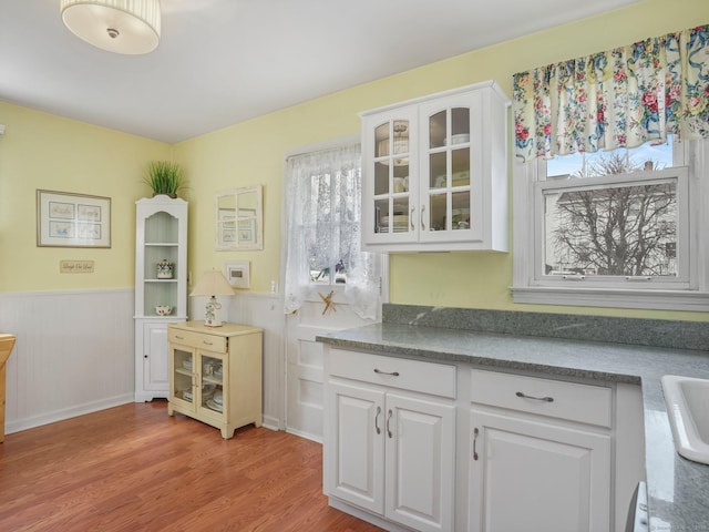 kitchen featuring wainscoting, white cabinets, and a healthy amount of sunlight